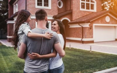 Back view of happy family is standing near their modern house and hugging